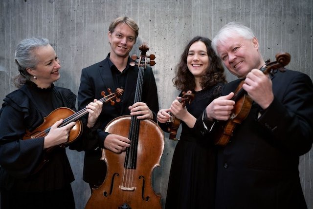 A string quartet holding their instruments.